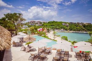 a pool with chairs and umbrellas next to a beach at Nirú Ocean Suites by Binniguenda in Santa Cruz Huatulco