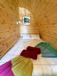 a bed in a wooden room with colorful blankets at LEIRIA Side Bungalow in Leiria