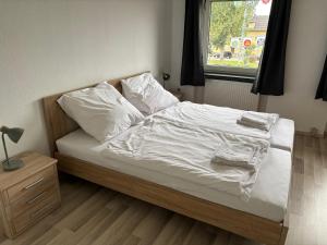 a bed with white sheets and pillows and a window at Pension DaVinci in Schwetzingen