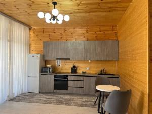 a kitchen with a table and a white refrigerator at Atlantis Resort Коттеджи-таунхаузы in Chon-Sary-Oy