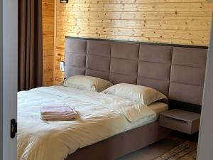 a bedroom with a large white bed with a wooden wall at Atlantis Resort Коттеджи-таунхаузы in Chon-Sary-Oy +21 photos