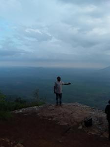 a man standing on top of a mountain with his arm out at Sheiza in Kampala