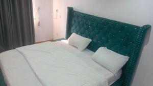 a white bed with a green headboard and two pillows at Monarch Appartement in Oshogbo