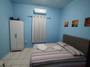 a blue bedroom with a bed and a refrigerator at Casinha de vó in Aracati