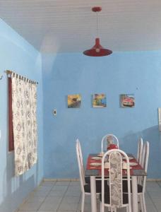 a dining room with a table and a blue wall at Casinha de vó in Aracati