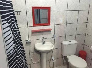 a bathroom with a toilet and a sink and a mirror at Casinha de vó in Aracati