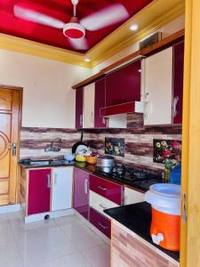 a kitchen with purple cabinets and a red ceiling at umer cottage in Murree