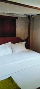 a bed with white sheets and a wooden canopy at Lola House in Lamu