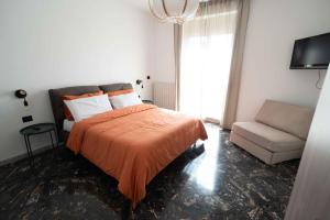 a bedroom with a bed with an orange blanket and a couch at Brighella in Putignano