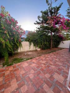 a brick walkway with a tree and pink flowers at Studio marina smir in Marina Smir