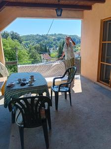 a man standing on a balcony with a table and chairs at Ljiljana Apartman 1 in Rakari
