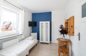 a bedroom with a white bed and a blue wall at Pokoje Złota Plaża in Międzywodzie
