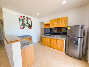 a kitchen with wooden cabinets and a stainless steel refrigerator at El Viento Beach Apartamentos in San Bernardo del Viento