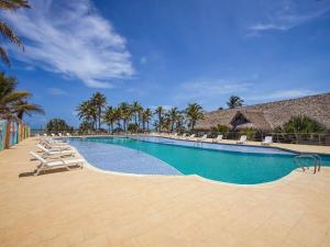 a large swimming pool with chairs and palm trees at El Viento Beach Apartamentos in San Bernardo del Viento