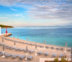 a beach with chairs and umbrellas and the ocean at Stunning Sea View in Central Postira in Postira