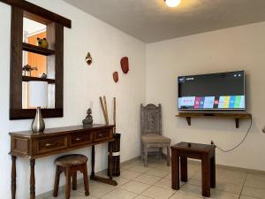 a living room with a tv and a desk and a chair at Casa Rincón Colonial I Confort y Tranquilidad in El Santuario