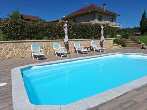 a pool with chairs and umbrellas next to a house at Lar de Mamita in Cristiñade