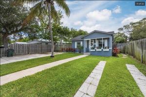 a small house in a yard with a fence at Endless Summer Cottage - Steps off Atlantic! in Delray Beach