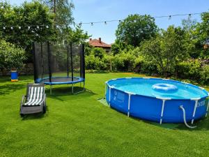 a pool with a table and a chair in a yard at Guest House Emiliya in Ovchartsi