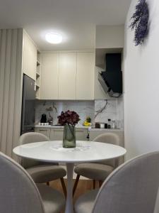 a white table with chairs and a vase of flowers at Stan na dan - SResidence Banja Luka in Banja Luka