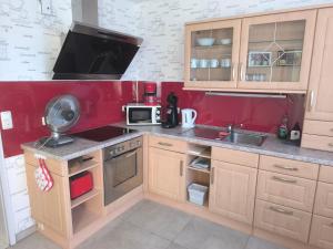 a kitchen with wooden cabinets and a red wall at Willy und Gudrun in Rheda-Wiedenbrück