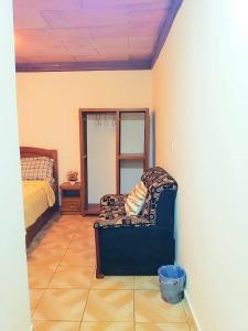 a bedroom with a bed and a chair in a room at M & S Multipurpose Center in Yaoundé