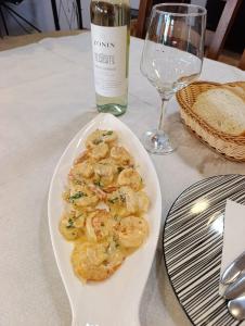 a plate of shrimp on a table with a bottle of wine at Jasmine Apartments in Velipojë