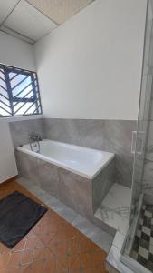 a bath tub in a bathroom with a shower at River Gates Home in Rundu