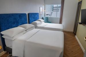 a hotel room with two beds and a blue chair at Faranda Collection Cali, a member of Radisson Individuals in Cali