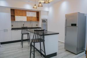 a kitchen with two bar stools and a refrigerator at Villa Ghizen in Fafou