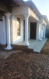 a white house with white columns and a patio at Lifeshed Guest Home in Johannesburg +1 photo