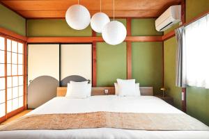 a bedroom with a large white bed with green walls at Nikko Botan - 3 Min Walk from JR Nikko Station in Nikko