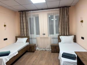 two beds in a room with two windows at Inju in Temirtaū