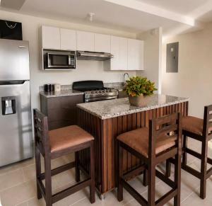 a kitchen with a counter with stools and a refrigerator at Apto de Paula in San Salvador