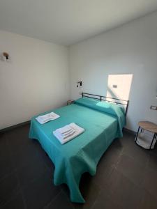 a bedroom with a green bed with towels on it at La dimora del borgo antico in Pulsano