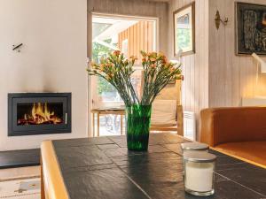 a vase of flowers on a table with a fireplace at 5 star holiday home in Væggerløse in Bøtø By