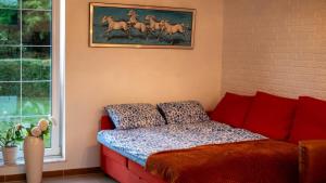 a bedroom with a red couch and a painting of horses at Amazing villa with garden in Kolding