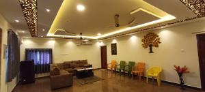 a living room with a couch and colorful chairs at white sand villa in Tirupporūr