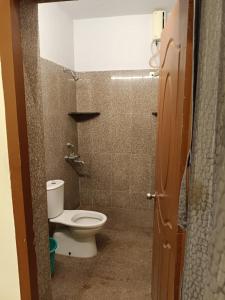 a small bathroom with a toilet in a stall at white sand villa in Tirupporūr
