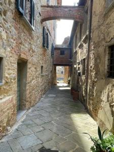 an alley between two stone buildings with an archway at Appartamento Monache in Lucignano