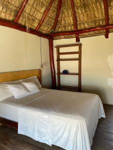 a bedroom with a white bed and a wooden ladder at Punta El Zonte in El Zonte