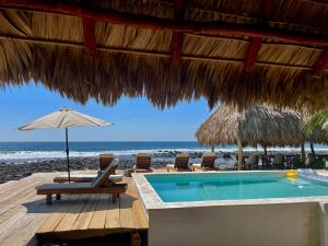 a resort with a swimming pool and chairs and an umbrella at Punta El Zonte in El Zonte