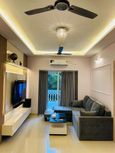 a living room with a couch and a ceiling fan at Verdant vista Goa in Cunchelim