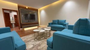 a waiting room with blue chairs and a tv at شقق احد رفيدة in Ahad Rafidah