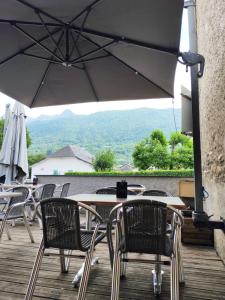 a patio with tables and chairs and an umbrella at L'Embaradere in Laruns