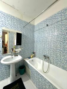 a blue tiled bathroom with a sink and a bath tub at Appartement près de la corniche in Sousse