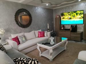 a living room with a white couch and a tv at Villa Harmonie - Suite Familiale avec Piscine in Khemisset