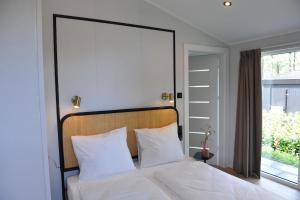 a bedroom with a bed with white sheets and a window at Luxe Boshuisje Lodge Wildblick, adults only Haarle, Sallandse Heuvelrug in Haarle
