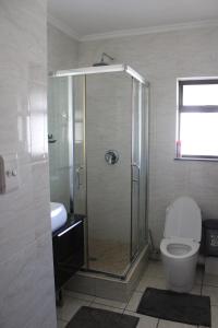 a bathroom with a shower with a toilet and a sink at First Gen Cedar Acres Fourways in Trevallyn +10 photos