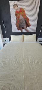 a woman is standing over a bed with a poster on the wall at Shivay Harmony in Birmingham